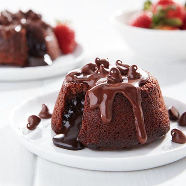 two plates with chocolate cakes and strawberries on the side, one has a bite taken out of it