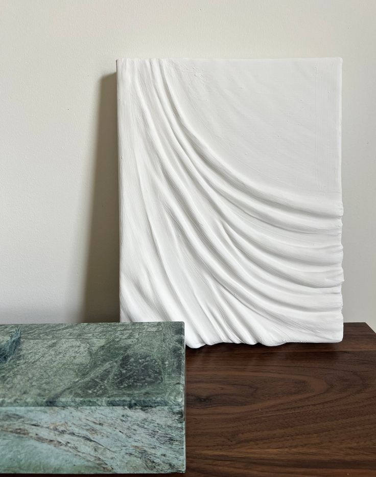 two pieces of marble sitting on top of a wooden table next to a white wall