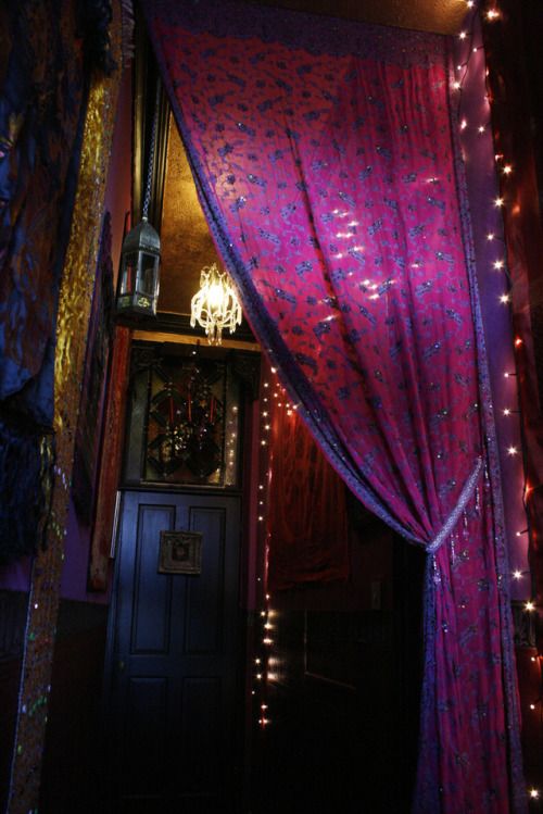 a room with purple curtains and lights on the walls, and a chandelier hanging from the ceiling