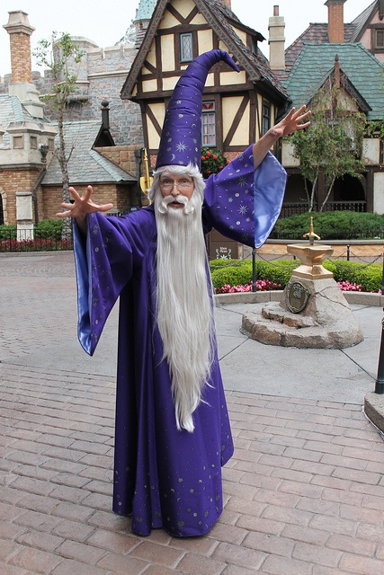 a man dressed as an old wizard standing in front of a house