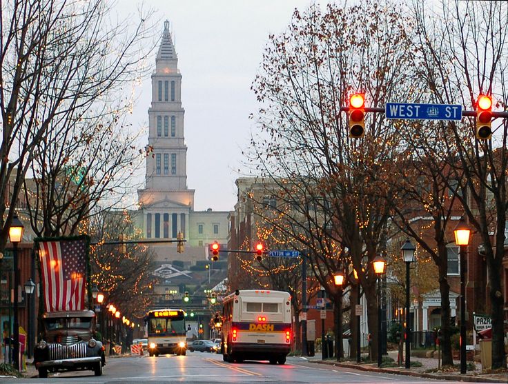 a city street filled with traffic next to tall buildings and trees on both sides of the road