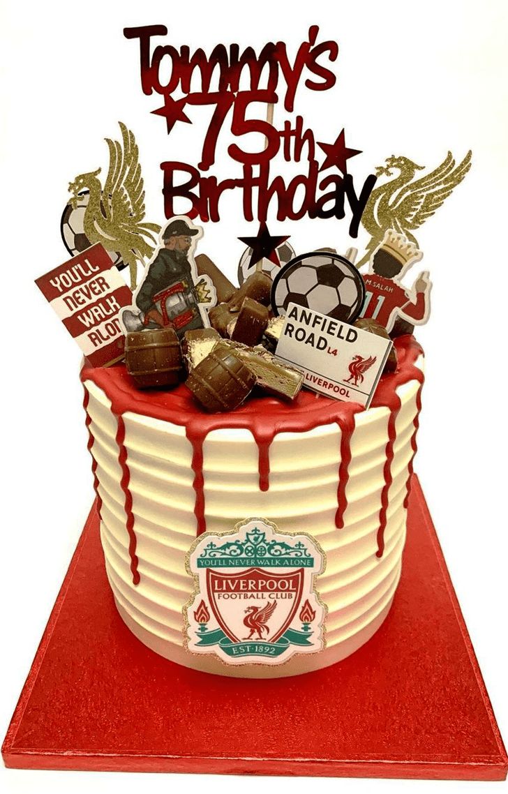 a birthday cake decorated with soccer memorabilia and sports related items on a red tablecloth