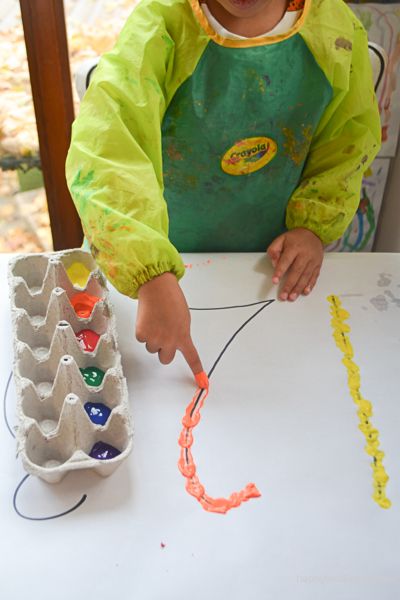 a young child sitting at a table with an egg carton in front of him