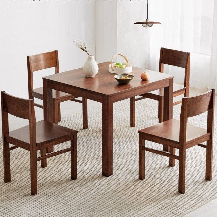 a wooden table with four chairs and a bowl of fruit on the dining room table