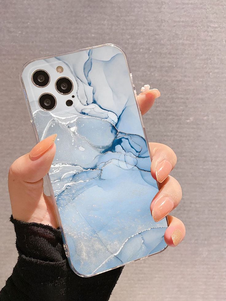 a woman holding up her phone case with an image of a blue marbled surface