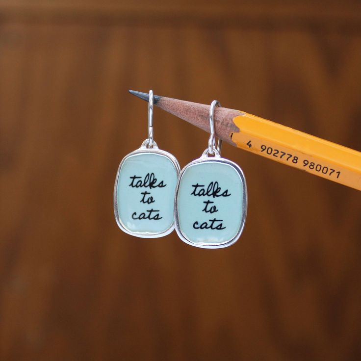 These funny cat earrings are perfect for your cat sitter or your favorite cat owner.  Adorable script written in enamel to last a lifetime. These sterling silver and enamel necklace measure about 3/4 of an inch tall and hang from a sterling silver French ear wires, for a total drop length of about 1 inch.  Each piece is cast in sterling silver, to which 3 layers of vitreous enamel are applied and fired. Finally, I apply and fire the custom screen prints made from my drawings. Adorable, durable, Personalized Cat Gifts, Glass Store, Vitreous Enamel, Custom Screen Printing, My Drawings, Cute Box, Enamel Necklaces, Unique Cats, Earrings Simple