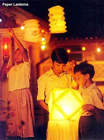 three people standing next to each other in front of a light that looks like an origami