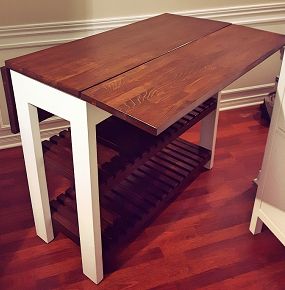 a wooden table sitting on top of a hard wood floor next to a wine rack