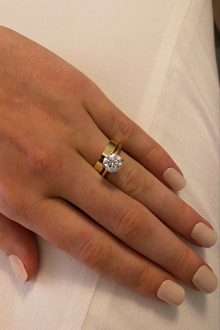 a close up of a person's hand with a diamond ring on their finger