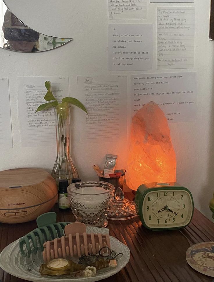 a table topped with lots of different items on top of a wooden table next to a clock