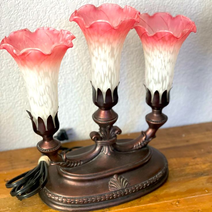 three pink and white vases sitting on top of a wooden table