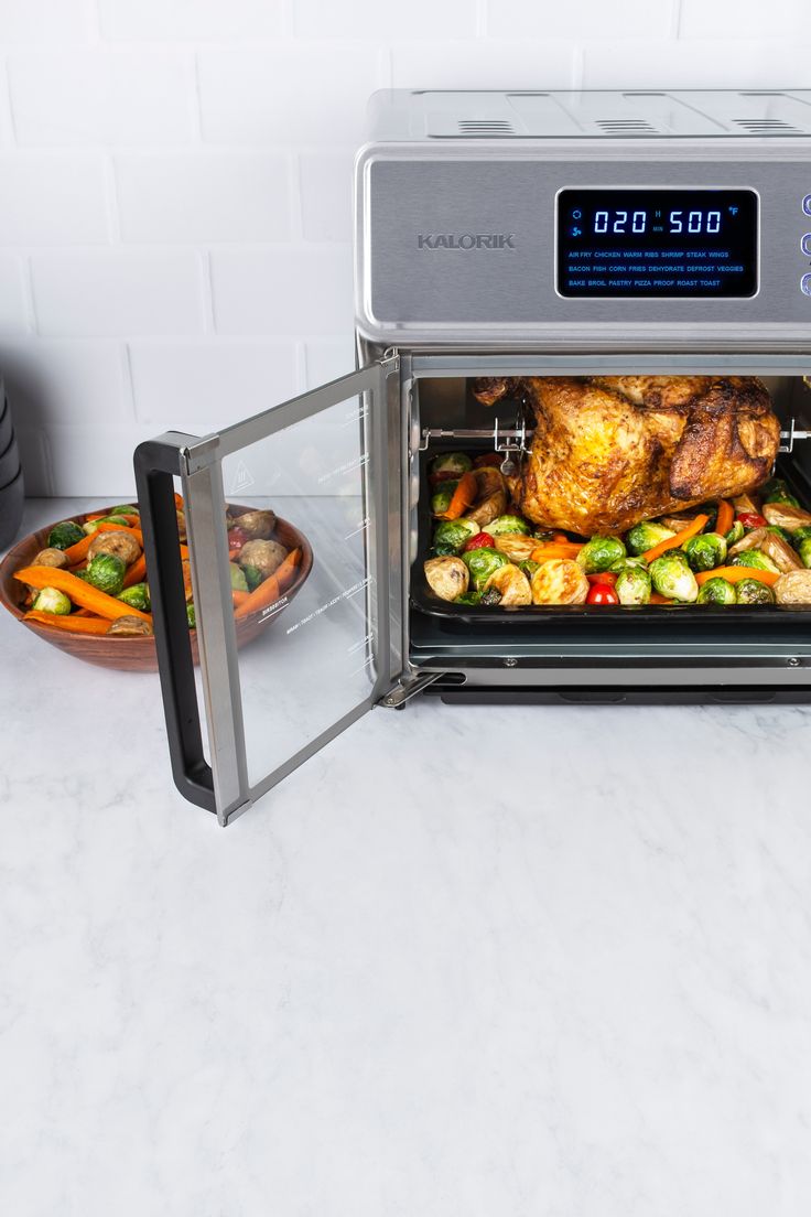 an open microwave oven with food in it on a counter next to a bowl of vegetables