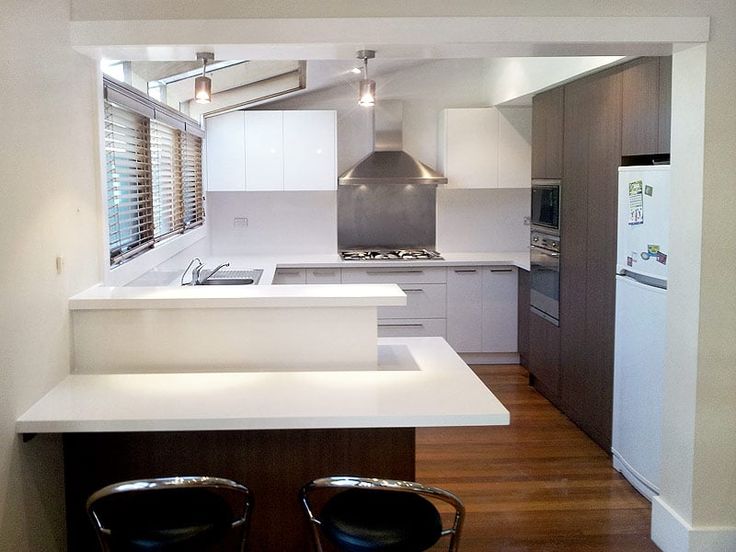 an empty kitchen with two stools next to the counter