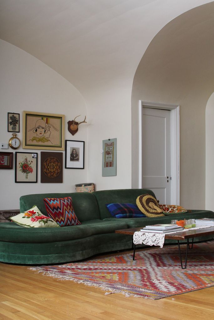 a living room with green couches and pictures on the wall above it's coffee table