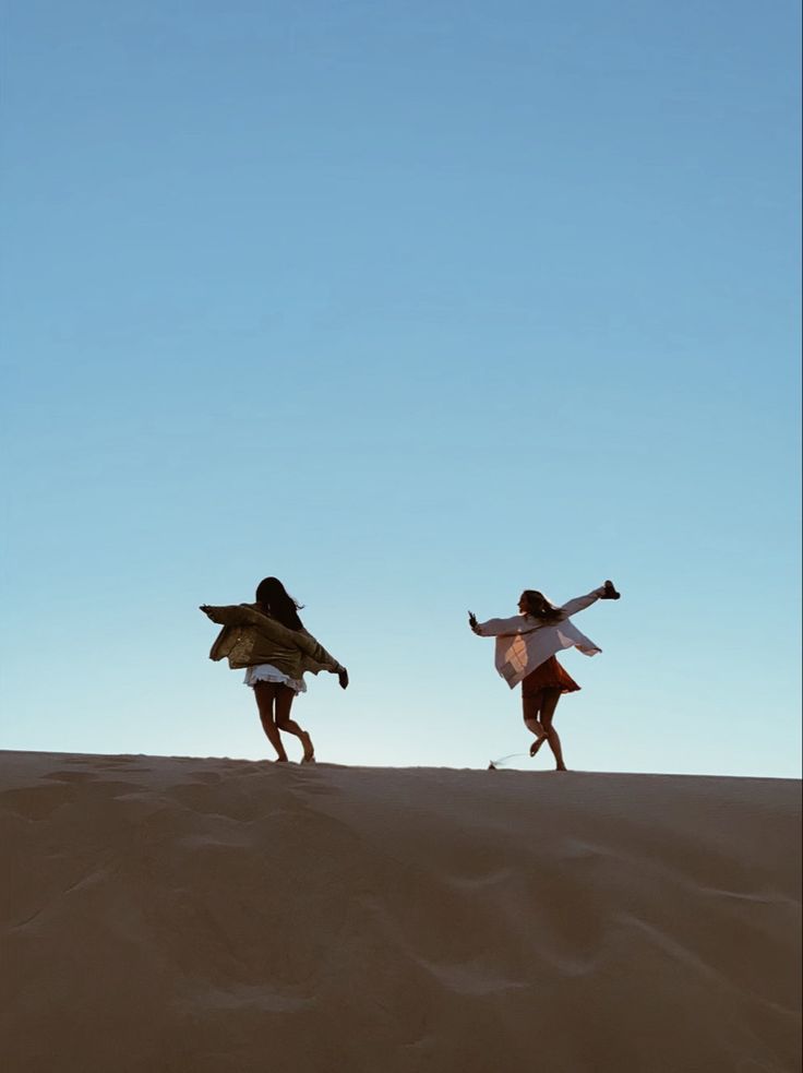 two people are running across the sand dunes