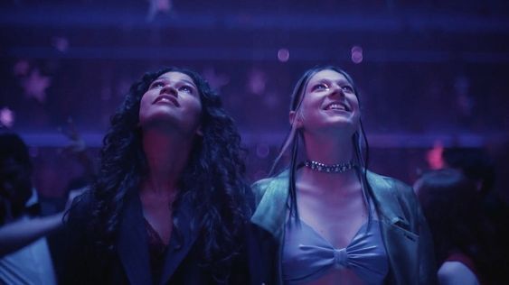 two women standing next to each other in front of a crowd at a club or nightclub