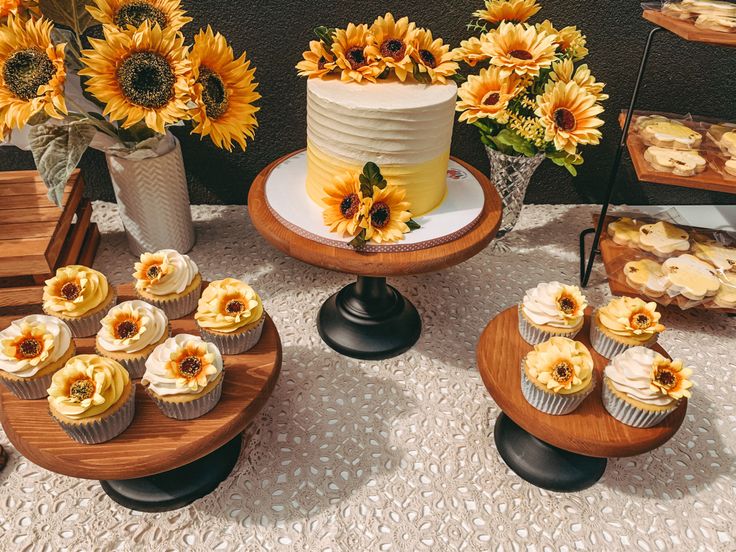 sunflowers and cupcakes are on display in front of a table full of pastries