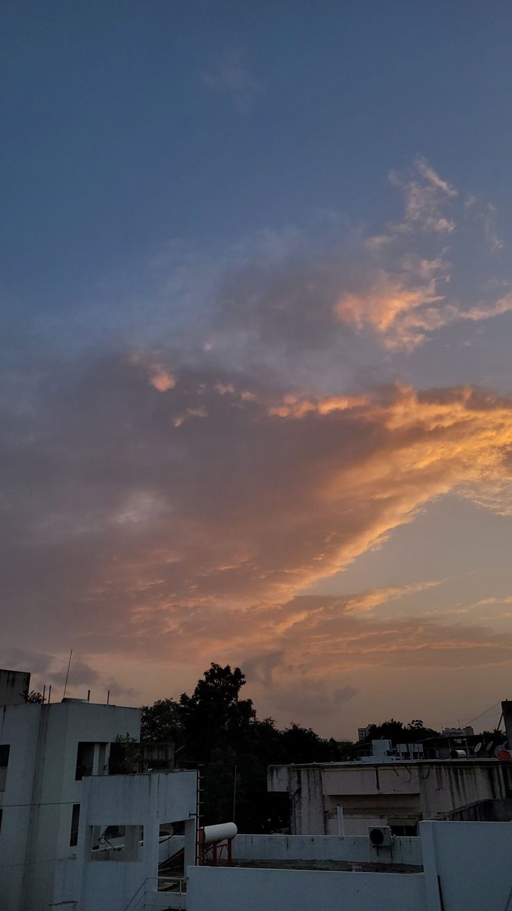 the sun is setting over some buildings and trees