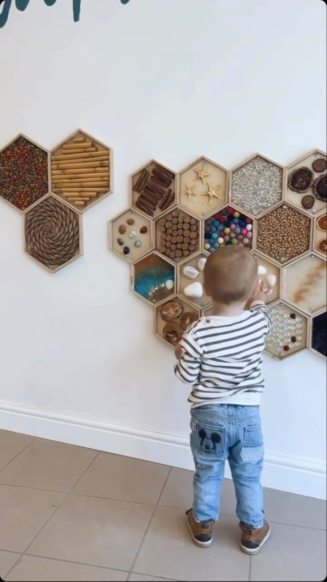 a little boy standing in front of a wall with hexagons on it