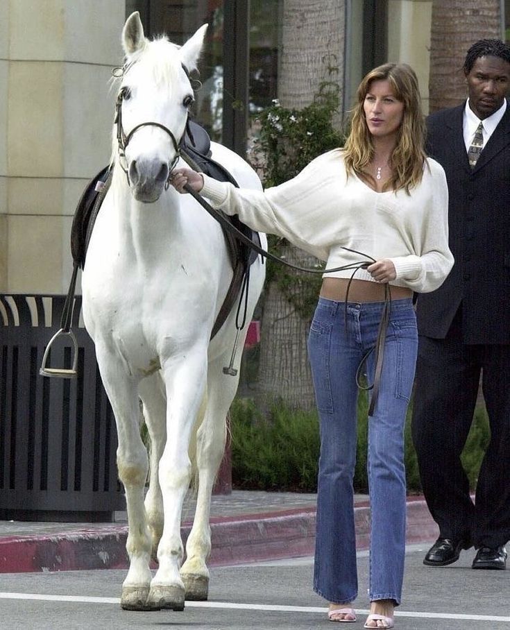 a woman is walking her horse down the street