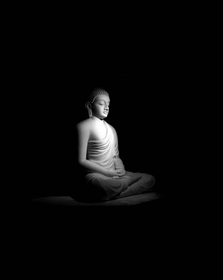 a buddha statue sitting in the middle of a dark room