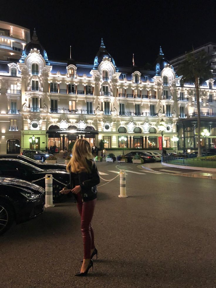 a woman standing in front of a large building with lights on it's sides