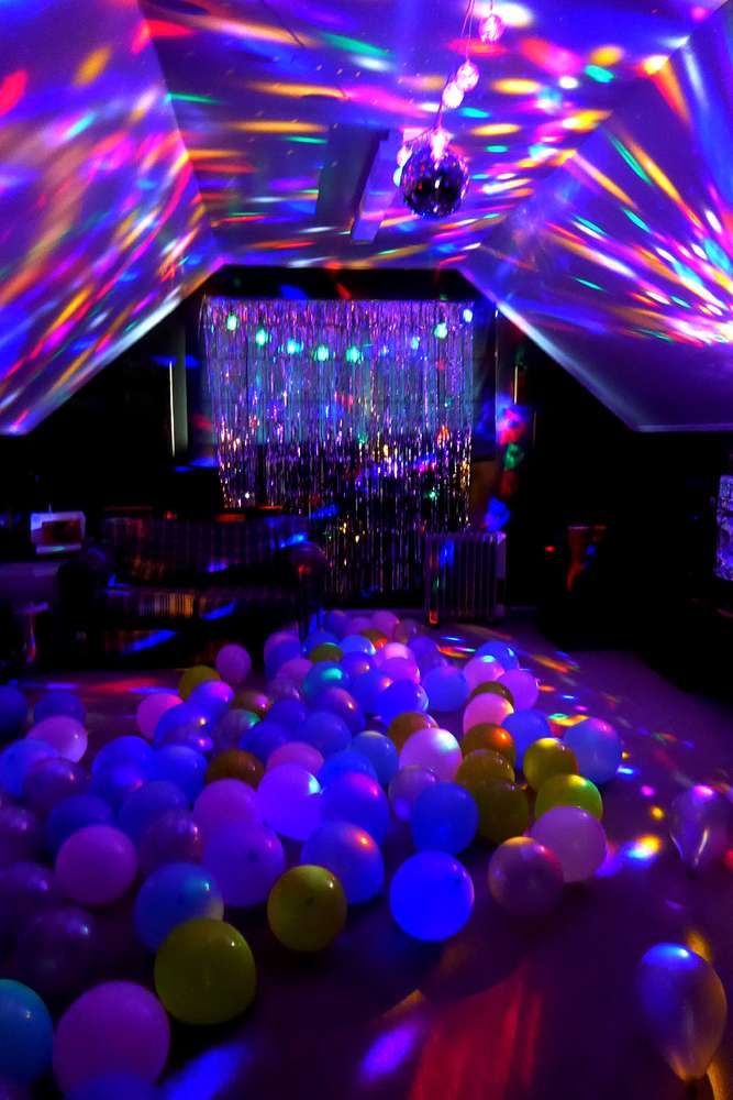 a room filled with lots of balloons and disco lights on the ceiling, all lit up