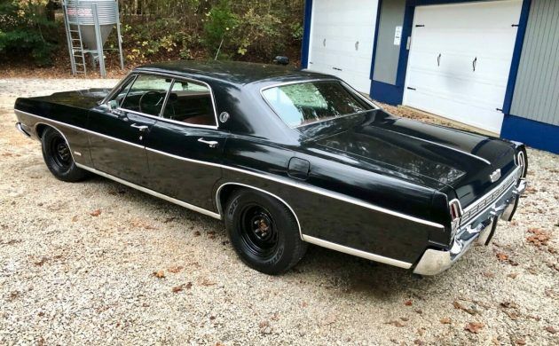 an old black car parked in front of a garage