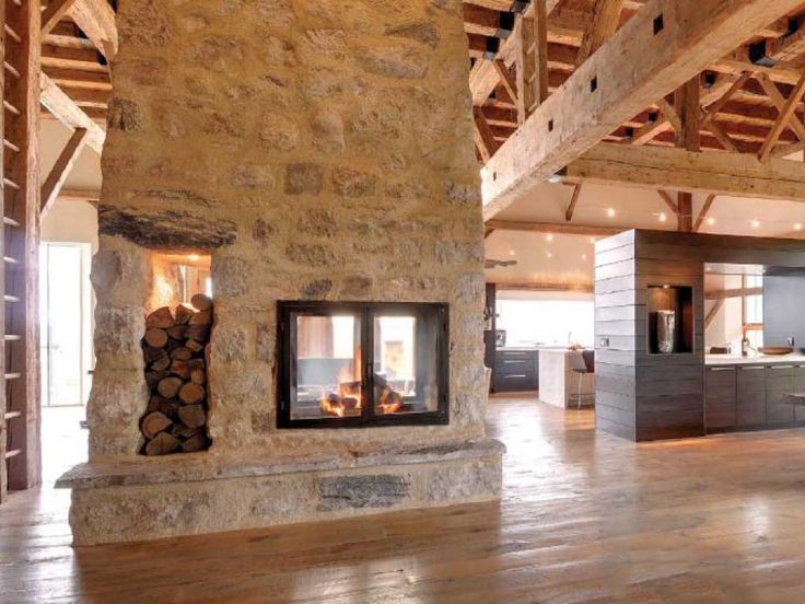 a living room filled with furniture and a fire place in the middle of a wooden floor