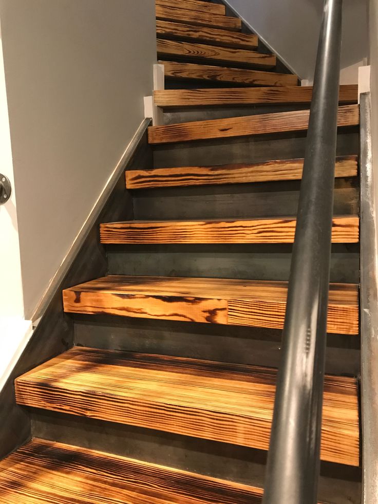 a set of stairs made out of wooden planks and metal handrails in a home