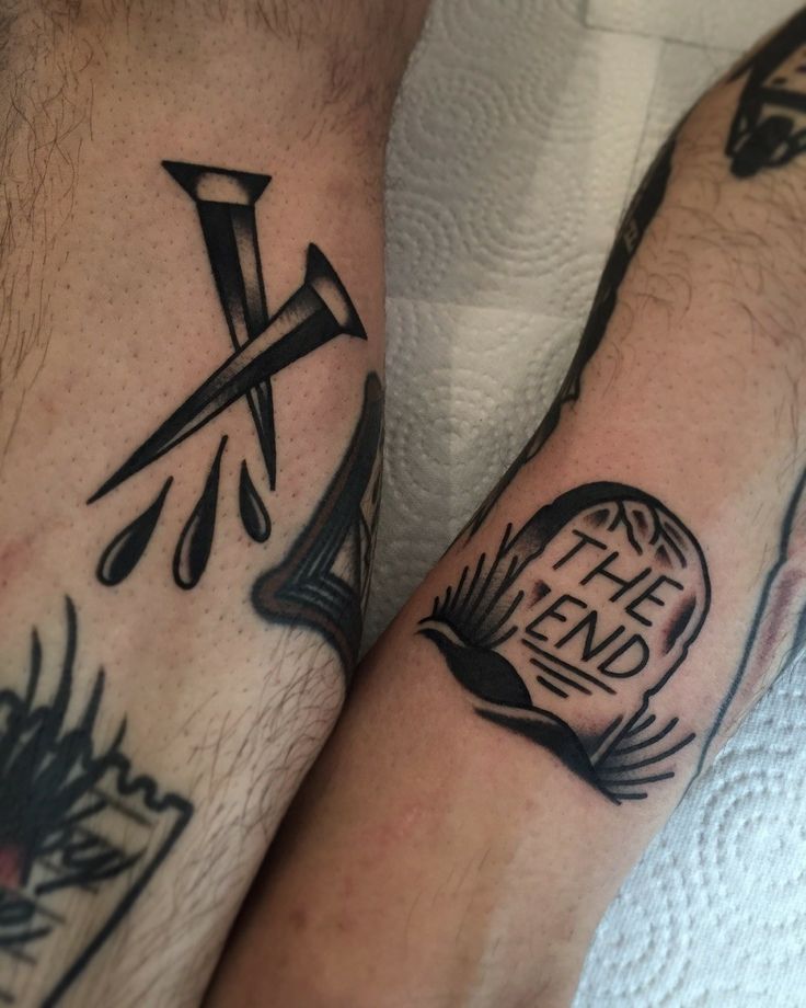 two men with matching tattoos on their arms, one has a cross and the other has a book