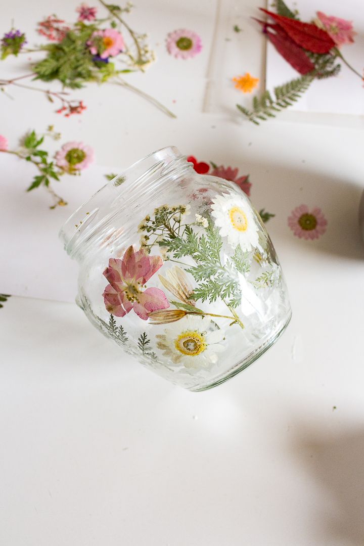 a glass jar with flowers painted on it