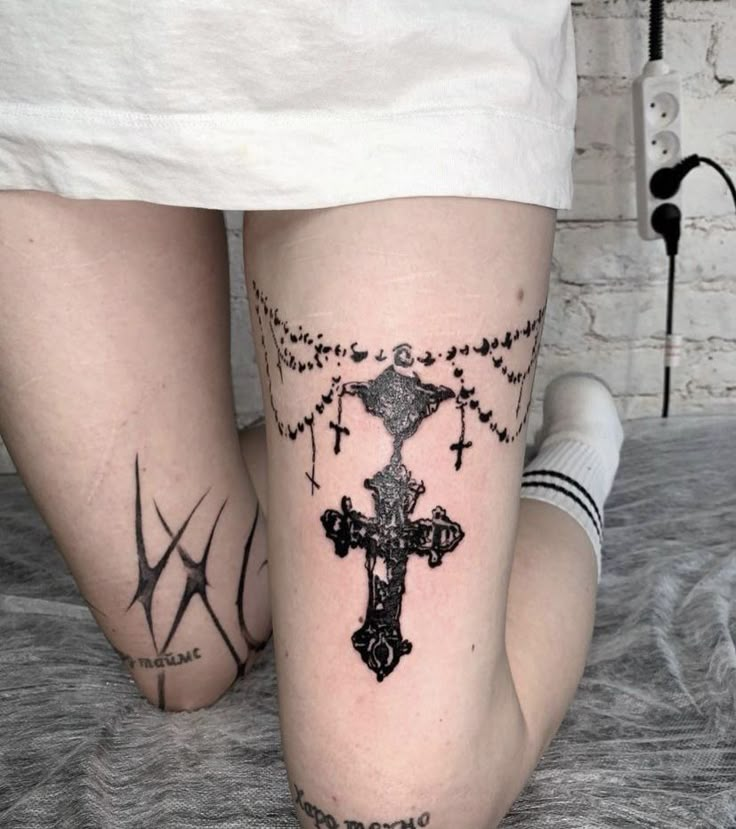 two people with cross tattoos on their legs