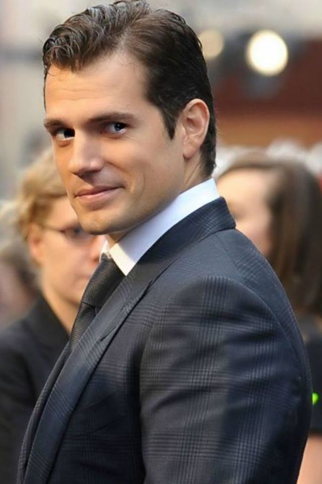 a man in a suit and tie posing for the camera with other people behind him