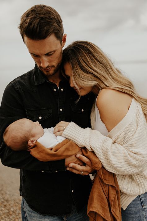 a man and woman holding a baby on the beach