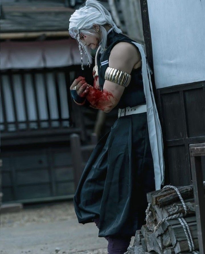 a man dressed in black and white with blood on his face standing next to a building