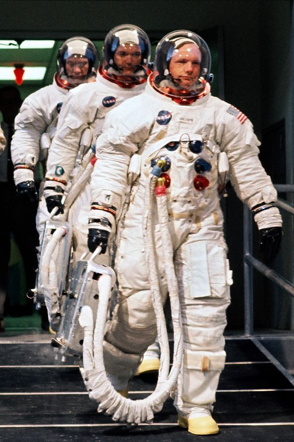 three men in white spacesuits walking down stairs with their hands on their hips