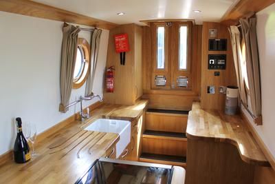 the inside of a sailboat with wood trimming and wooden flooring, windows, and sink