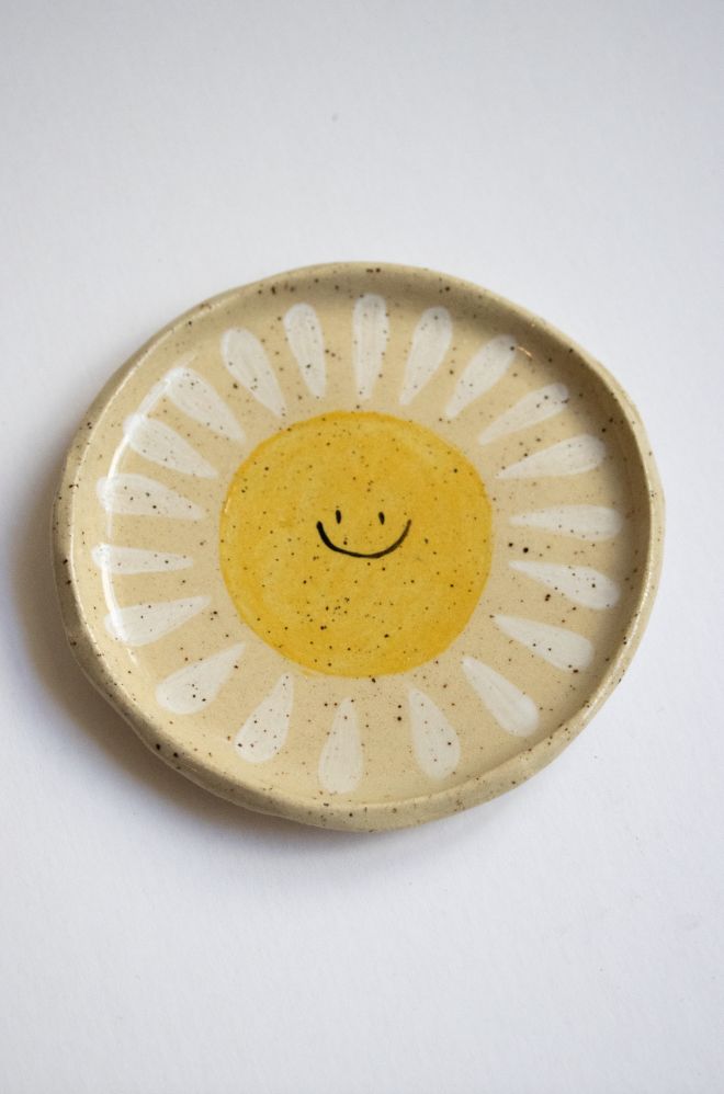 a yellow and white plate with a smiley face painted on the front, sitting on a white surface