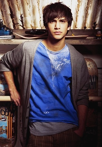 a young man standing in front of a book shelf