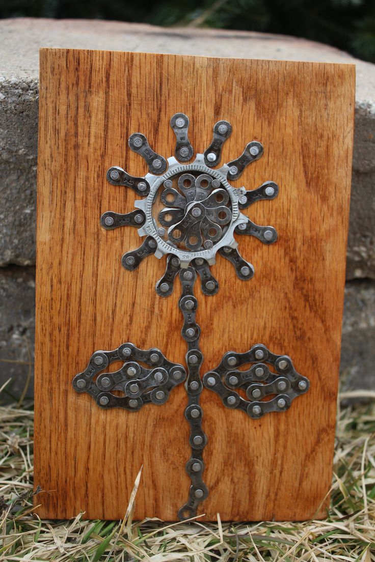 a wooden box with metal designs on it sitting in the grass next to a stone wall