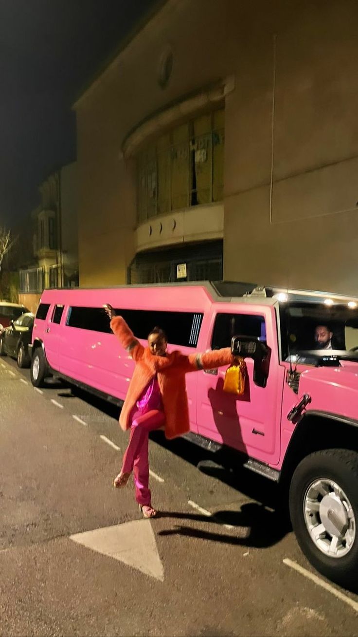 a pink limo is parked on the side of the road in front of a building