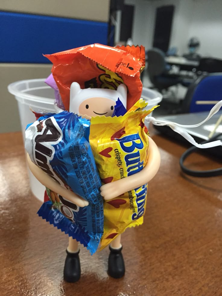 a small toy holding a bag of chips on top of a table