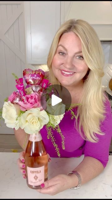 a woman holding a bottle of wine with flowers in it