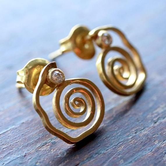 Many cultures embellished the ears with spiral shapes, the Met literally has hundreds of them. But the Sinú culture of Colombia did it with style. Hand worked gold vermeil (gold-plate over sterling silver) with cubic zirconia accent. Size: 1/2 inch tall. Yellow Gold Swirl Earrings For Gift, Swirl Yellow Gold Earrings For Gift, Spiral Cubic Zirconia Jewelry For Anniversary, Swirl Shaped Sterling Silver Jewelry In Gold Color, Gold Spiral Jewelry, Spiral Gold-plated Jewelry, Gold Plated Spiral Jewelry, Spiral Yellow Gold Jewelry With Diamond Accents, Spiral Yellow Gold Jewelry For Anniversary