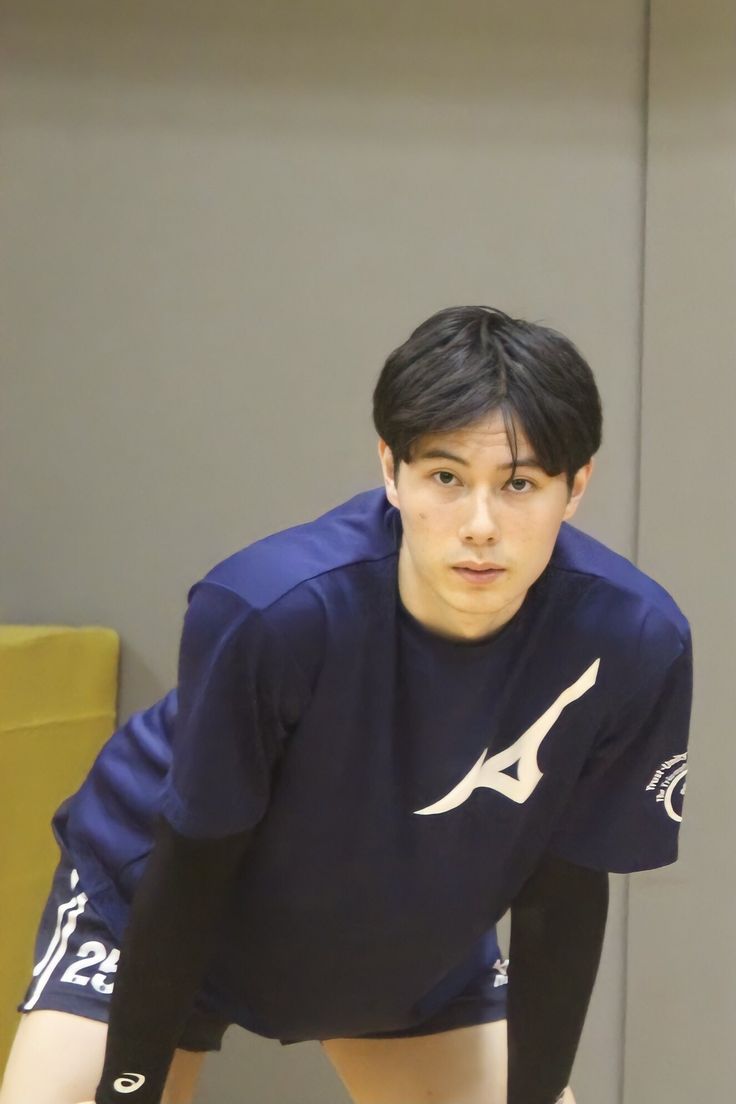 a young man holding a tennis racquet on top of a hard wood floor