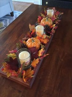 a wooden table topped with candles and fall leaves on it's centerpieces