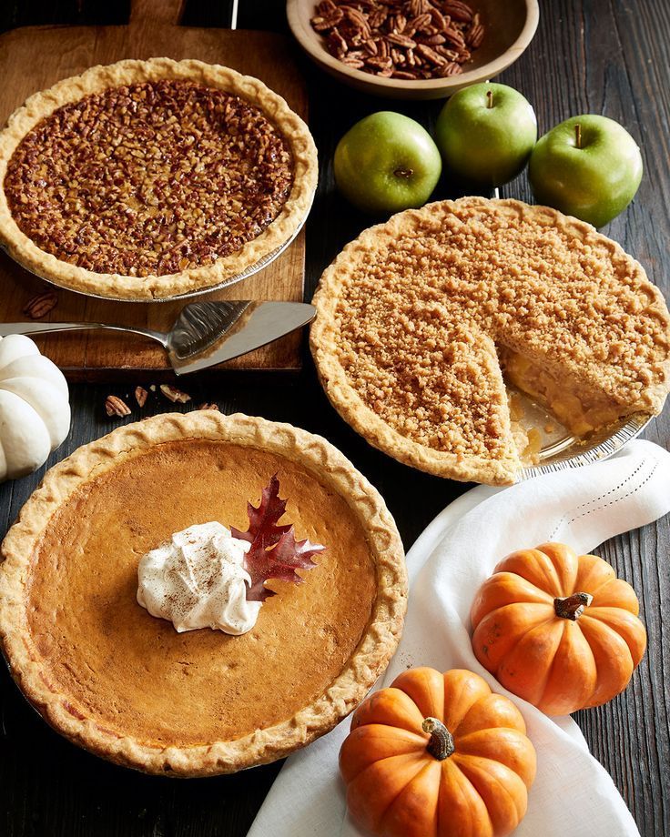 several pies, apples and pumpkins on a table