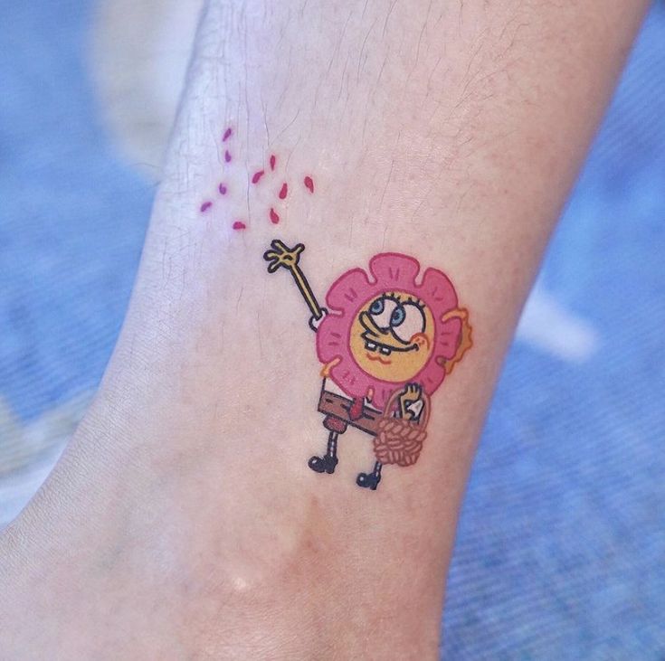 a small tattoo on the foot of a person with a pink flower and an arrow