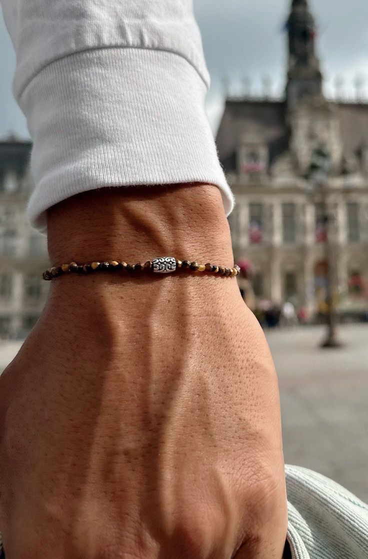 A Tiger Eye Beaded Bracelet for Men with a that is made with a silver metal part at the center in ethnic philosophy and minimal dimensions. All these materials are passed through an elastic cord. You can select between four available dimensions.  FInd them at Christina Christi Store. 👉 My Mens Bracelets Collection: https://etsy.me/2UunKla 👉 Express Shipping: https://etsy.me/3ikUnOM MATERIALS - Tiger Eye Beads 3mm. - Metal Parts. - Elastic cord. DIMENSIONS - You can choose four different dimens Sneakers Outfit Men, Minimal Bracelet, Diy Bracelets Tutorials, Thread Bracelets, Bracelet Mens, Bracelet Men, Tiger Eye Beads, Handmade Wire Jewelry, Mens Beaded Bracelets